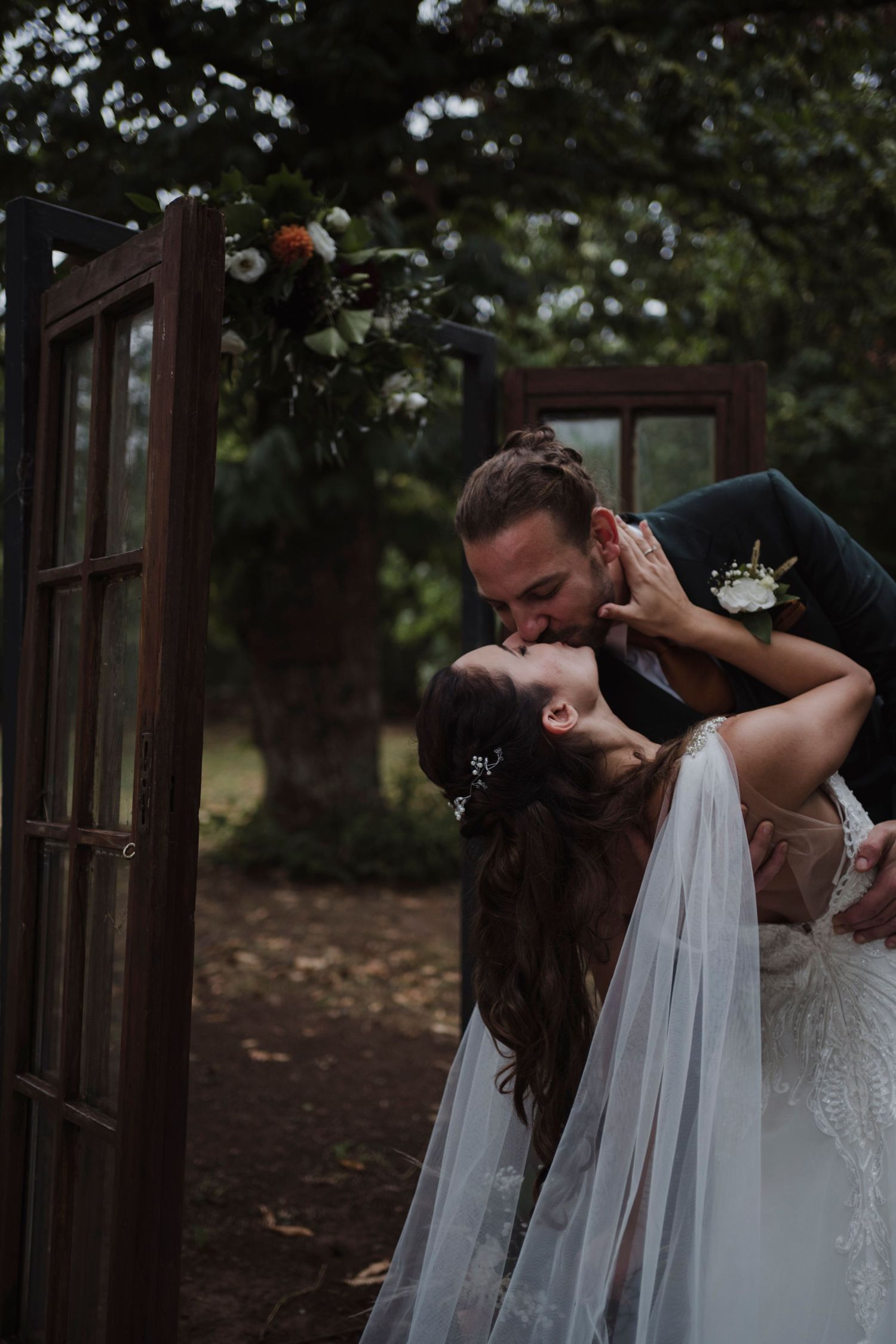 An intimate wedding portrait of a couple in a dramatic dip pose near wooden doors.