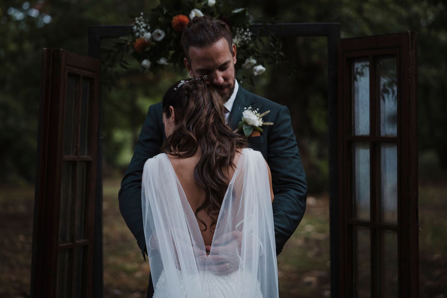 A romantic moment between newlyweds by vintage wooden doors in a forest setting.