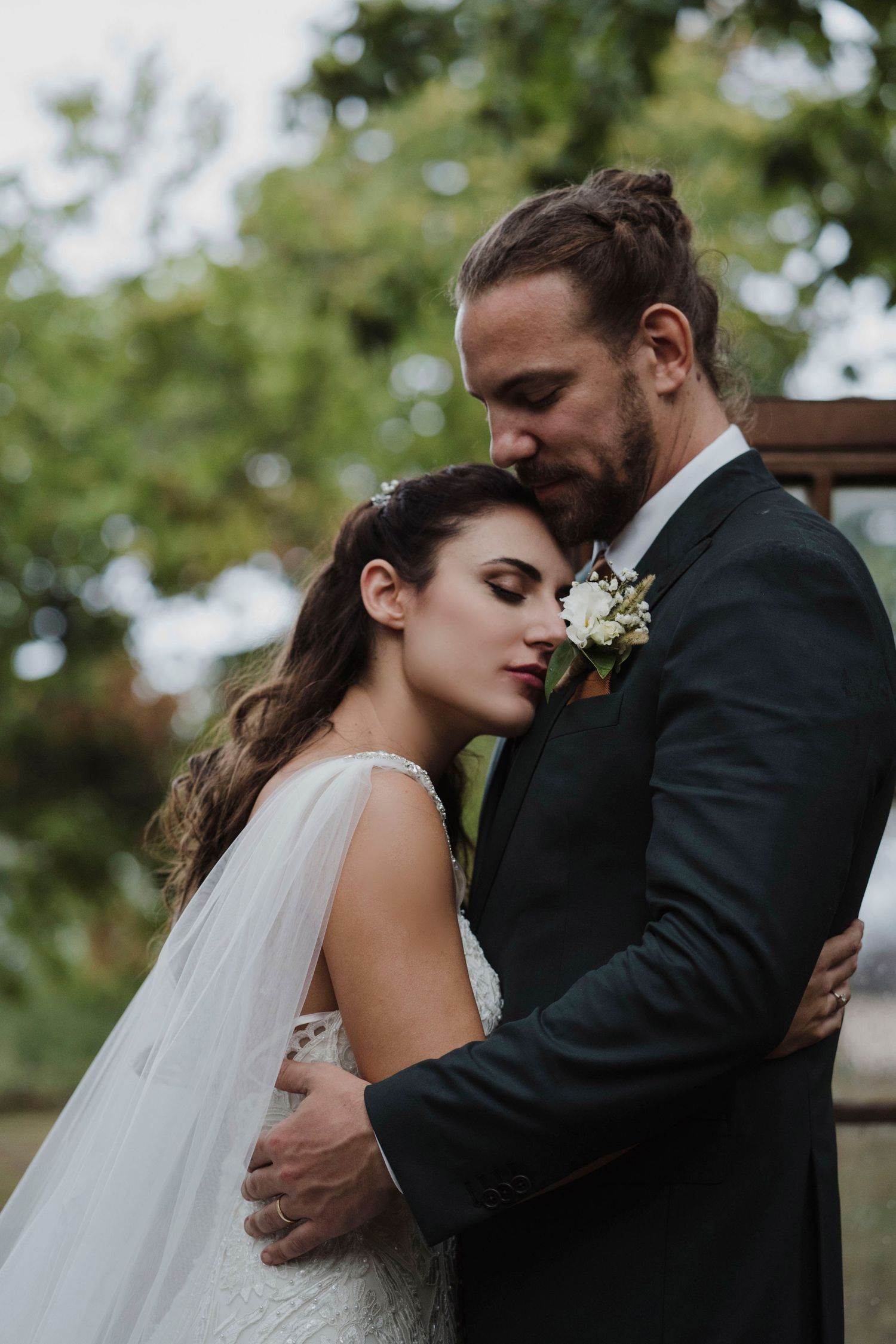 A romantic moment between newlyweds as they embrace outdoors in formal wedding attire.