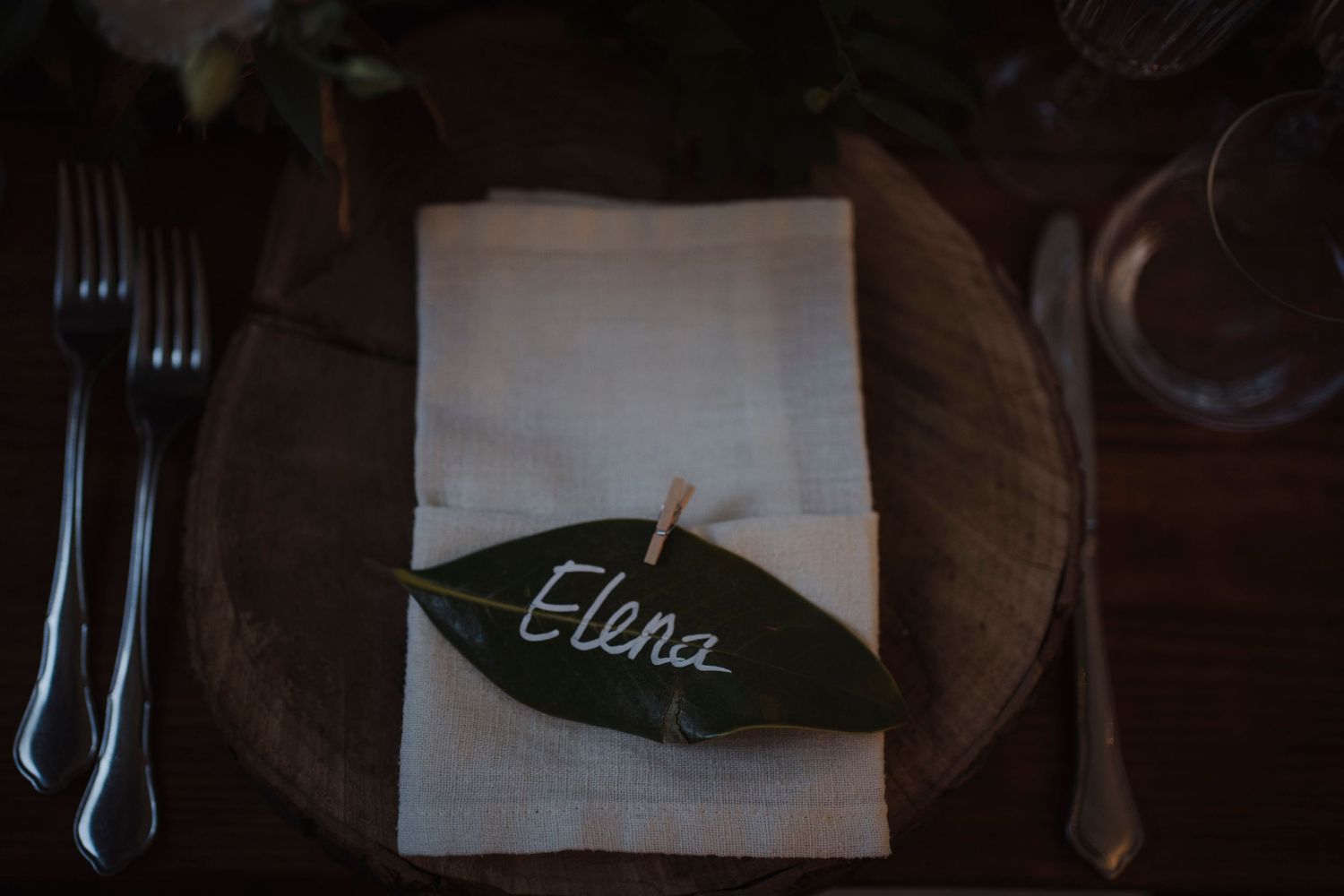 Place setting with white napkin and green leaf name card marked Elena.