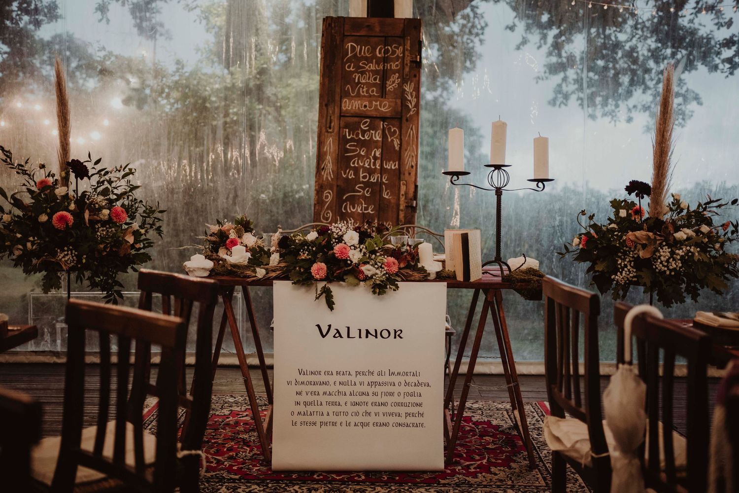 Rustic wedding display with Valimor sign, candles, and floral arrangements in moody lighting.