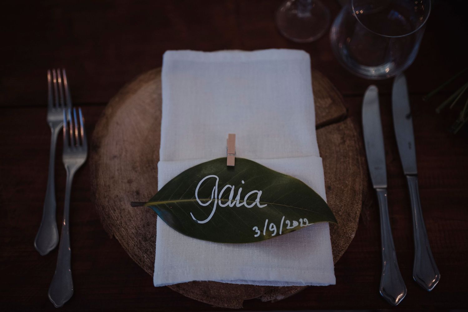 Elegant place setting featuring white napkin with green leaf name card marked Gaia.