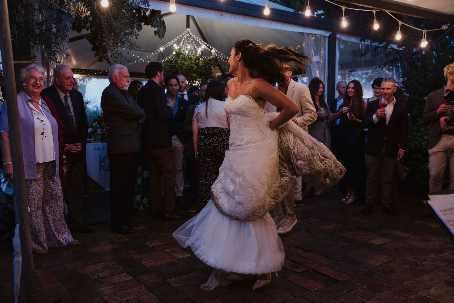 Couple dancing at twilight reception with guests watching in the background.