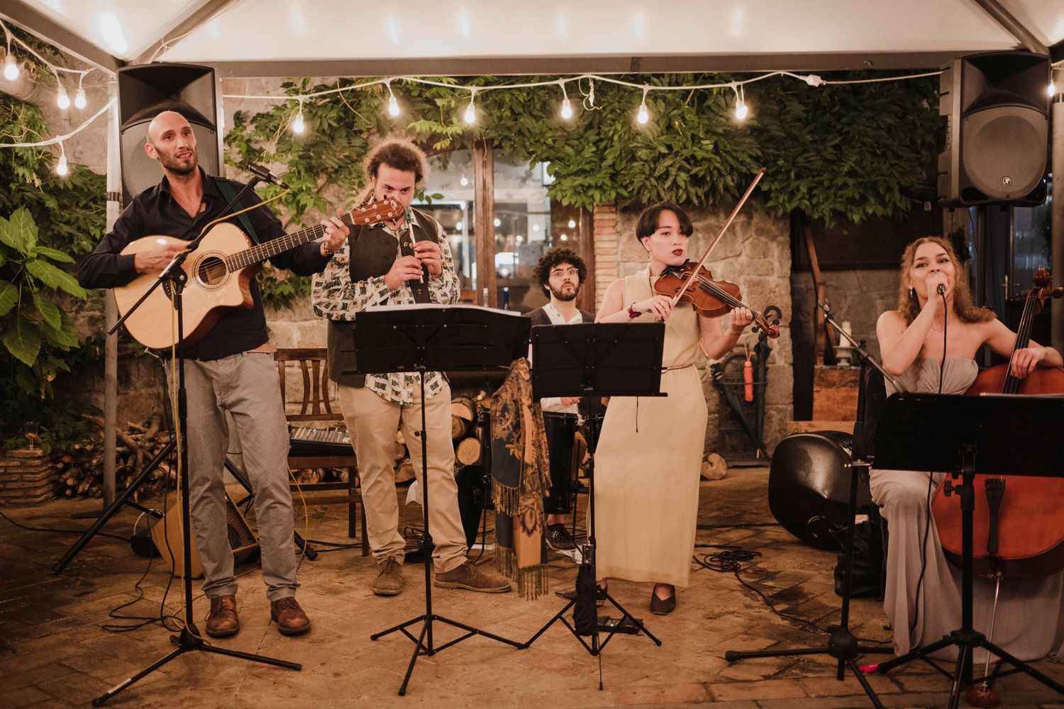 Live band performing with instruments and music stands at a decorated indoor venue.