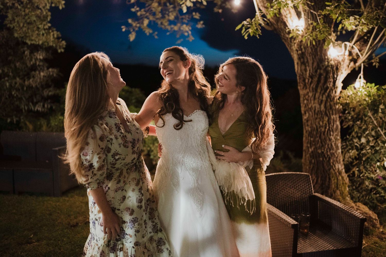Joyful outdoor evening celebration with guests in formal attire sharing laughter.