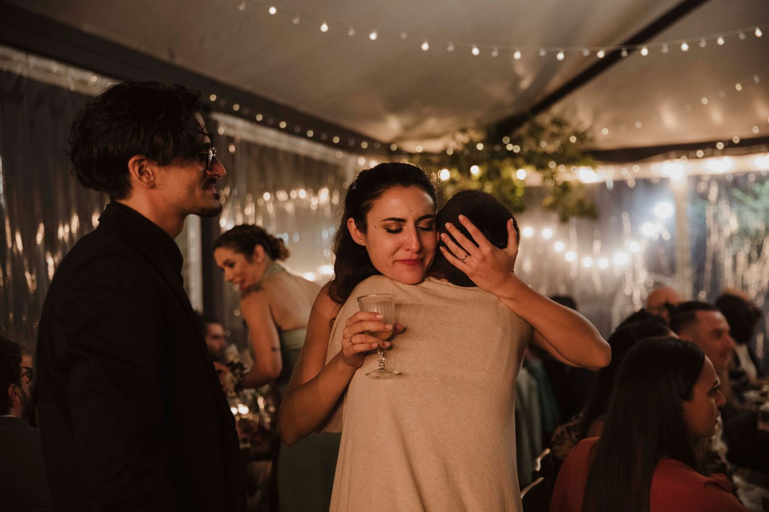 Intimate moment between guests dancing at an indoor reception with string lights overhead.
