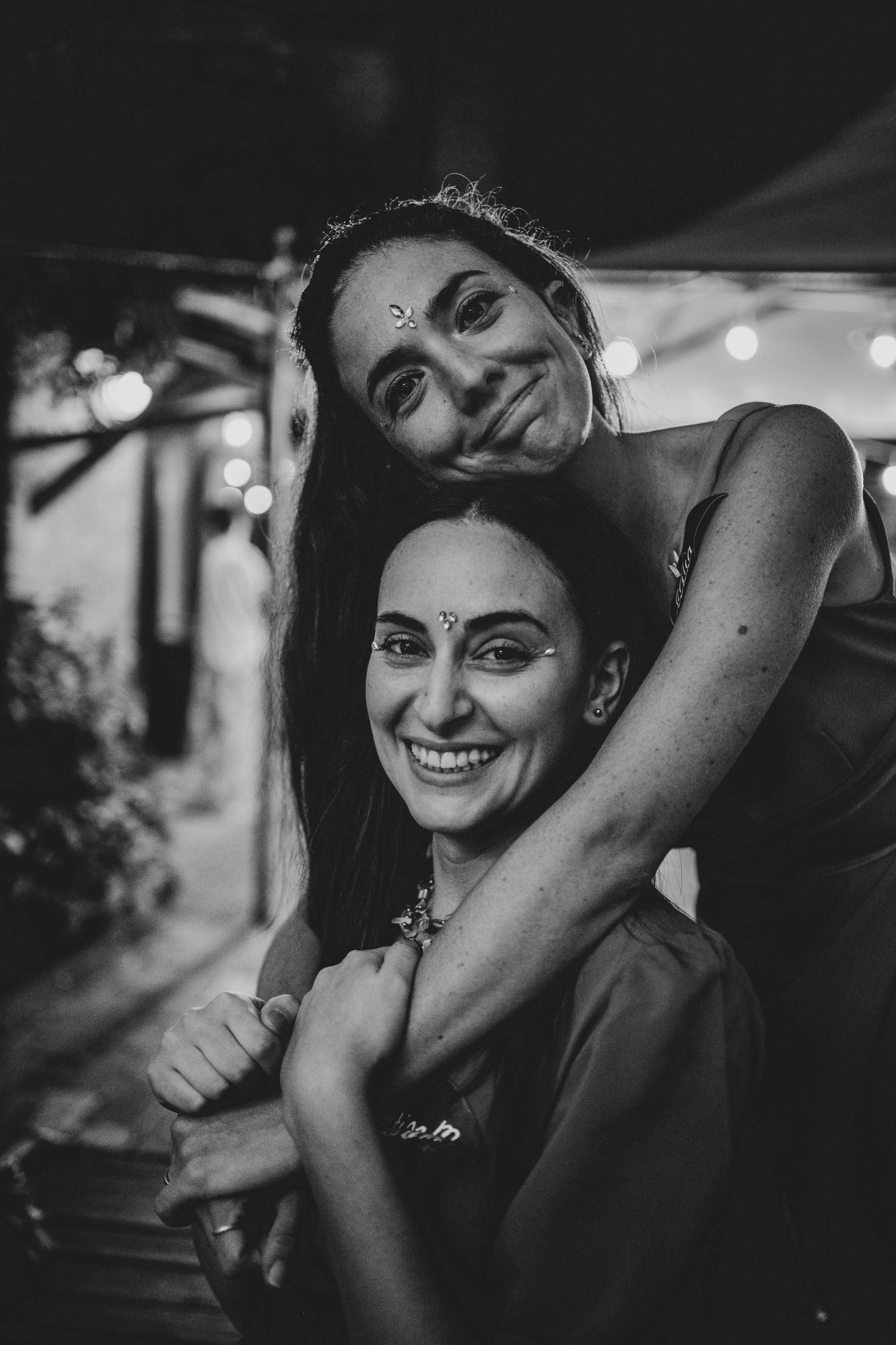 Black and white candid photo of two friends embracing at a celebratory event.