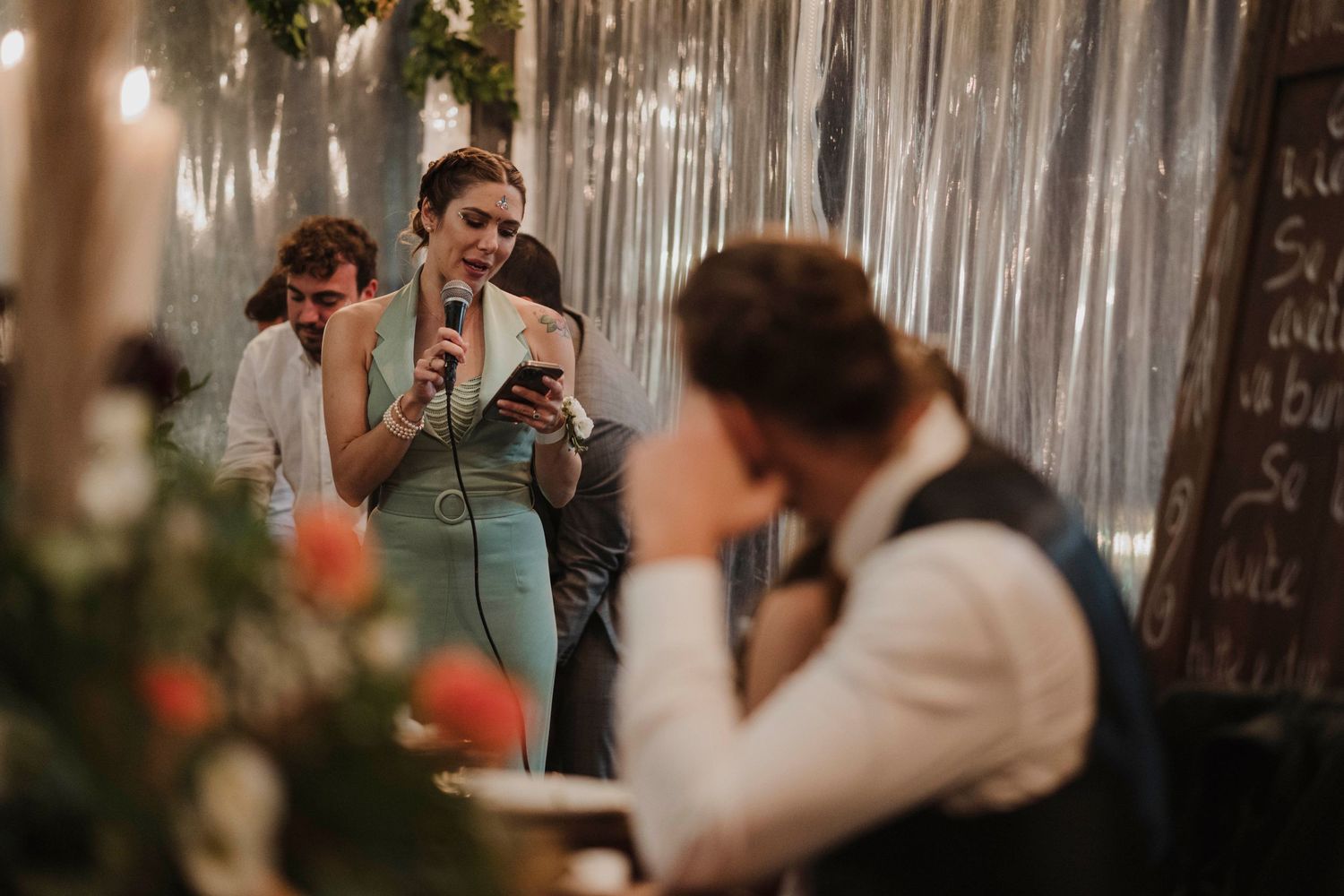 Guests mingling at a celebration with silver streamers and decorative lighting in the background.