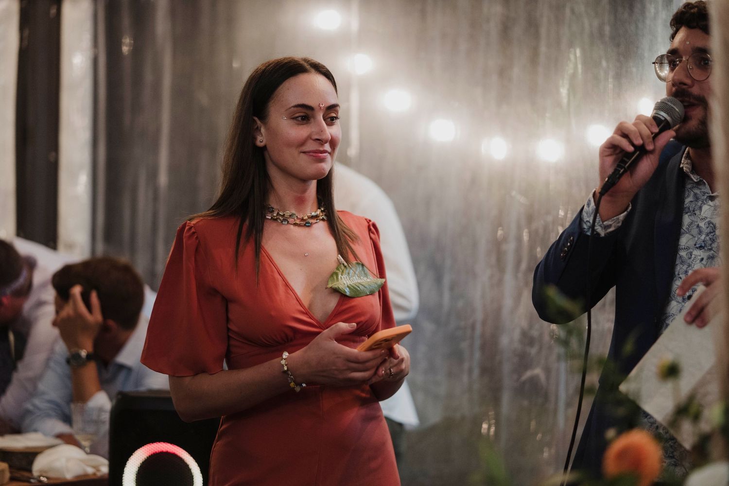 Guest enjoying drinks and conversation at an elegant evening event under sparkly lighting decorations.
