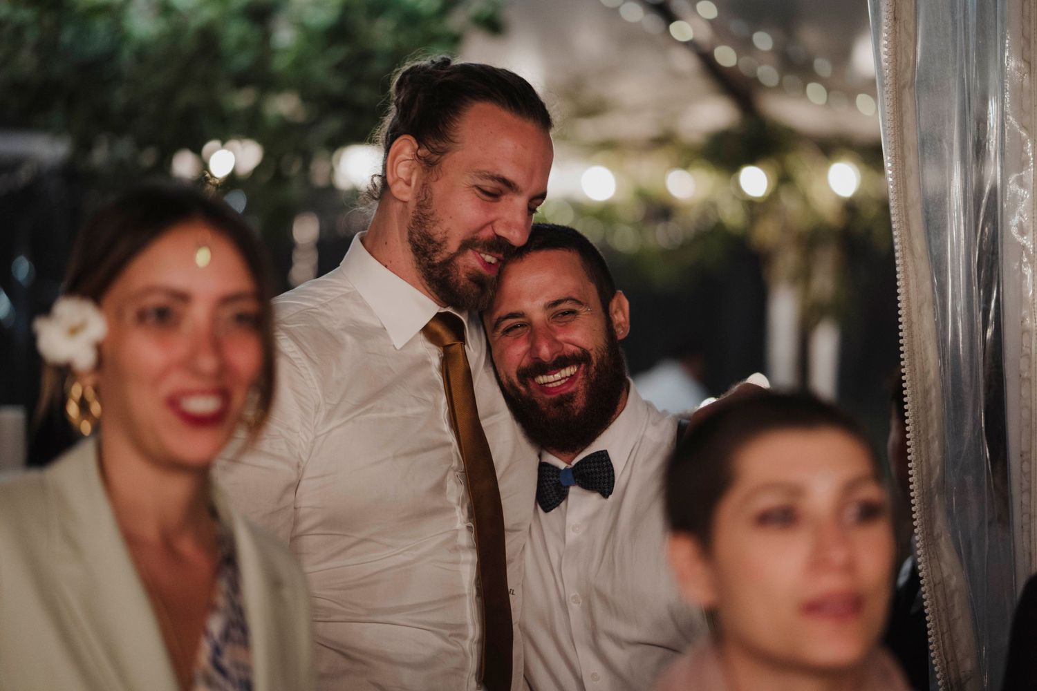 Wedding reception guests sharing joyful laughter during evening celebrations.