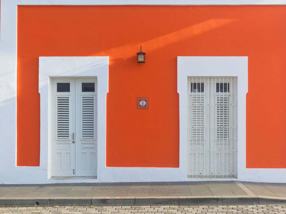 Orange wall with white shuttered windows creating geometric pattern.