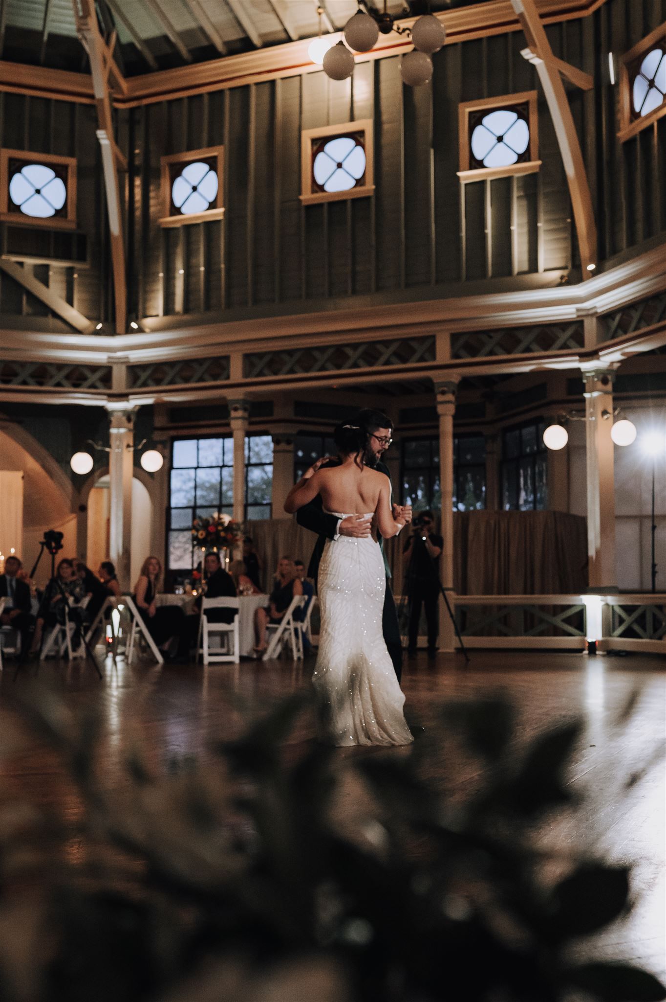 Wedding couple dancing in elegant venue with dramatic lighting and architectural details.