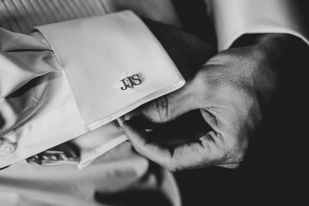 Close-up detail shot of monogrammed shirt cuff during wedding preparations.