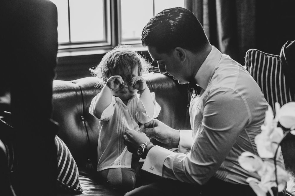 A tender black and white moment between parent and child sitting together on a leather couch.