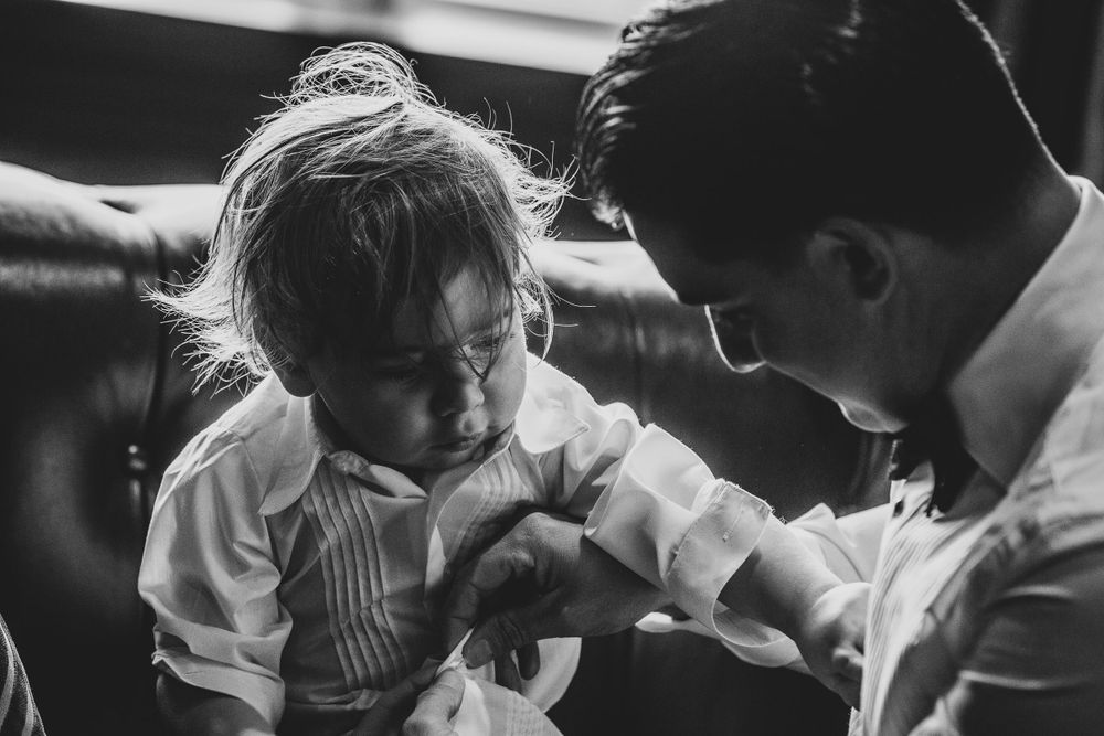 Black and white candid photo showing a tender moment between a child and adult in a soft, intimate setting.