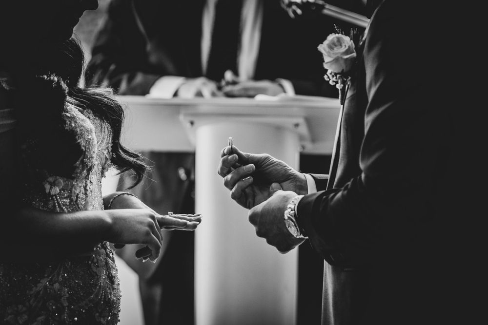 Black and white photo of a minister performing Catholic communion service during a wedding ceremony.