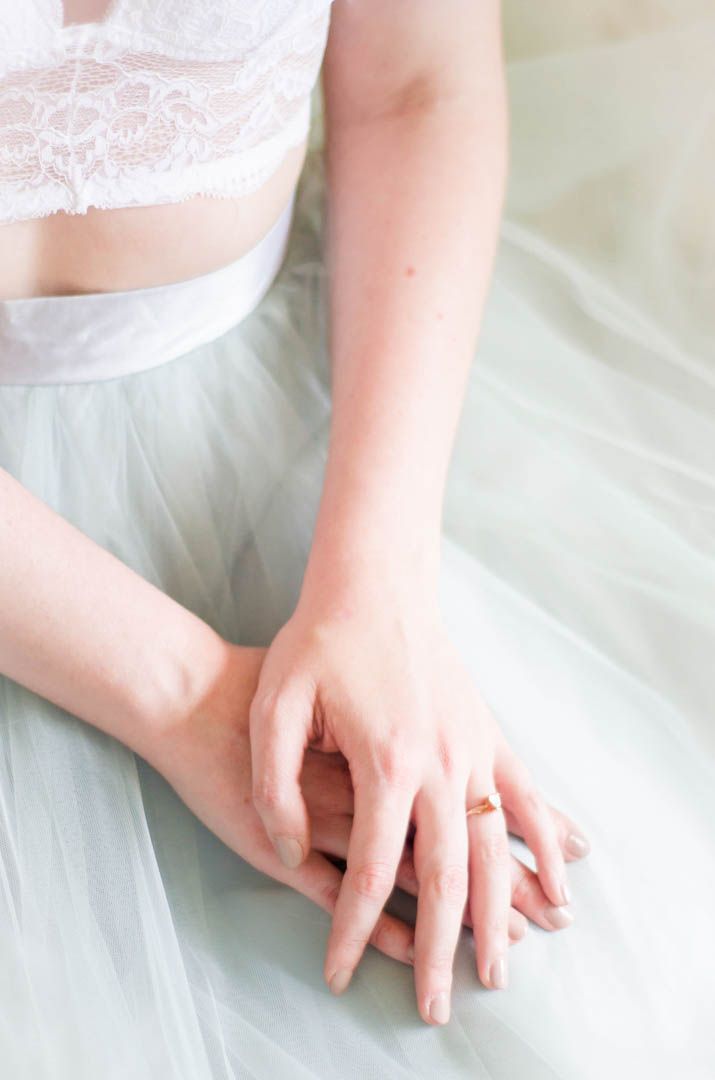 Close-up of delicate hands against white tulle fabric.