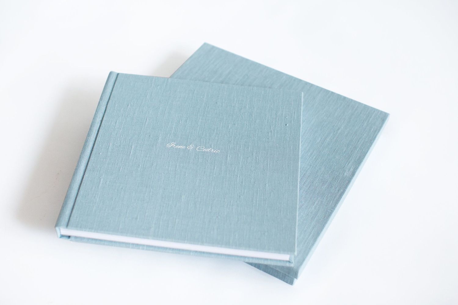 Two light blue hardcover photo albums stacked at an angle on white background.