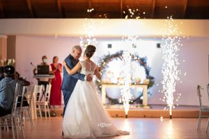 Bride and groom share first dance surrounded by sparkling fountain fireworks at elegant wedding reception.