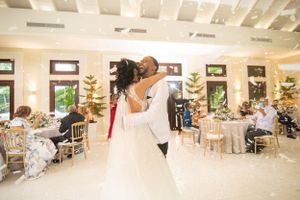 Bride and groom share joyful first dance embrace at elegant decorated wedding reception hall.
