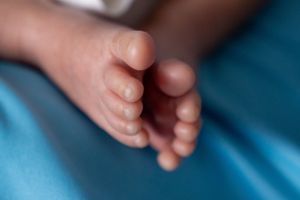 Close-up of tiny baby feet against blue background.