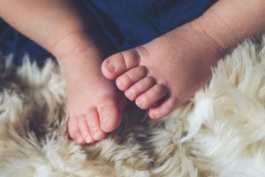 Close-up of tiny baby feet resting on soft white fur.