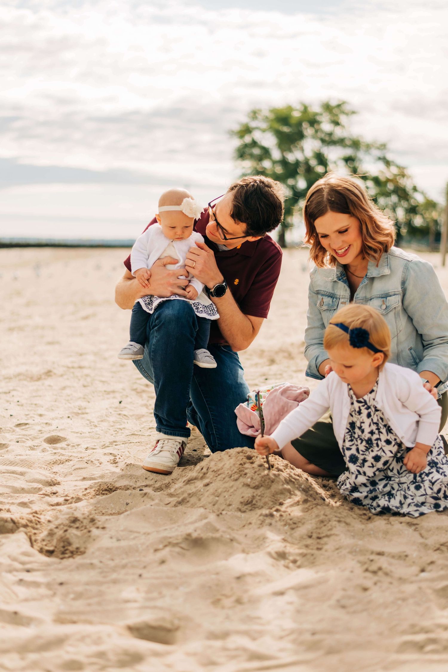 mother, father, and two little girls playing in the sand at the beach