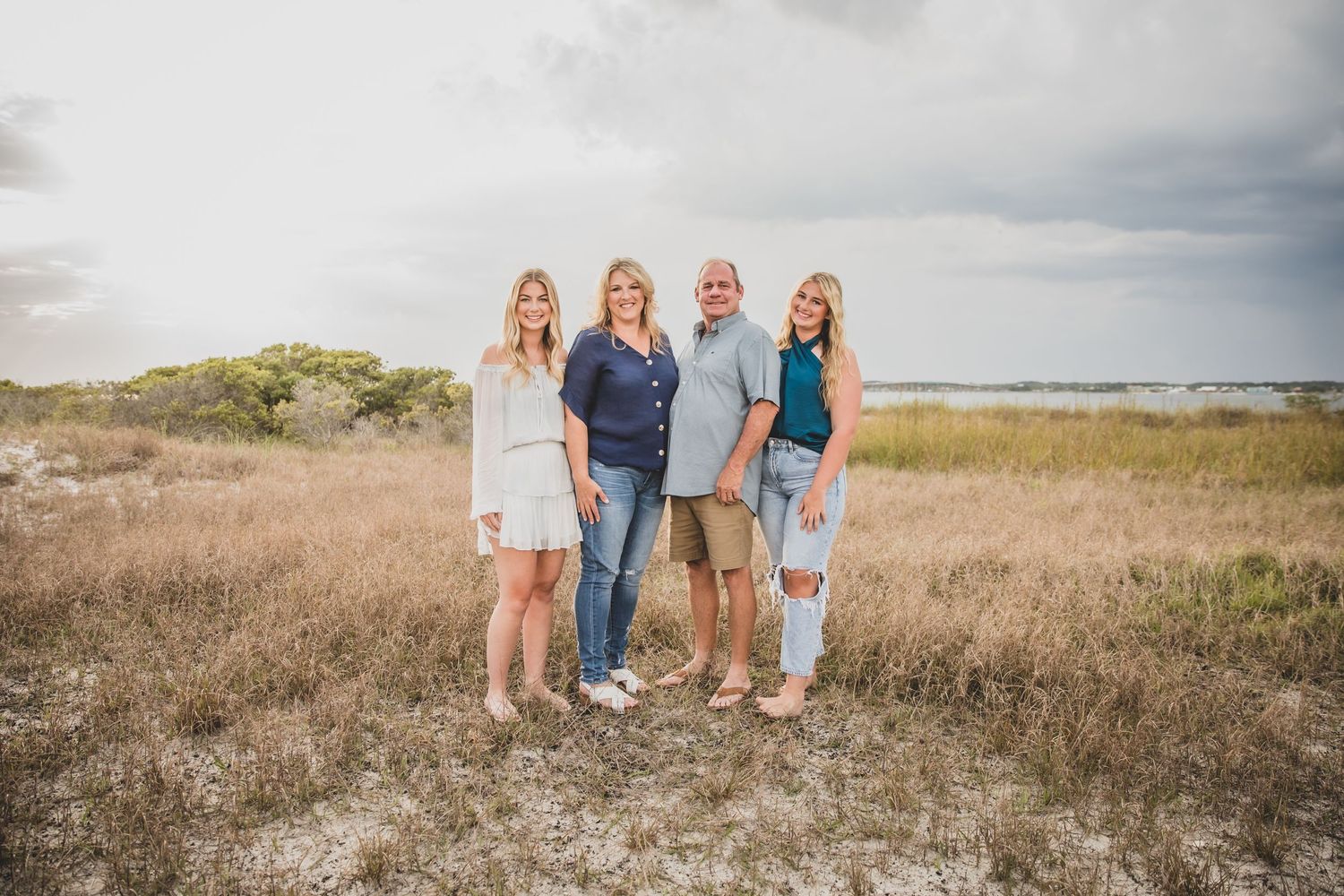 A group poses together on a sandy beach during golden hour with the ocean waves visible in the background.