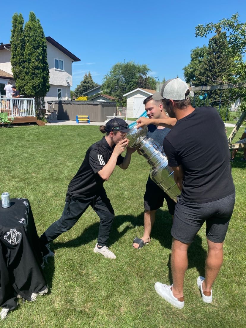 Two people playfully having a water bottle fight in a backyard on a sunny day.