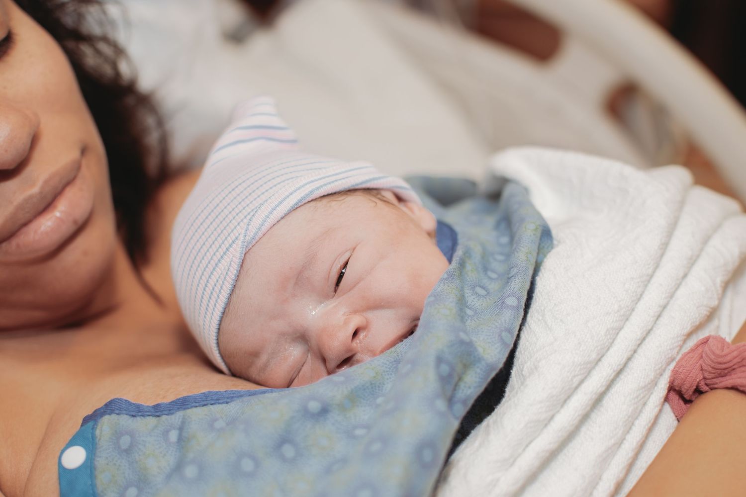 A newborn baby sleeping peacefully wrapped in white blankets.
