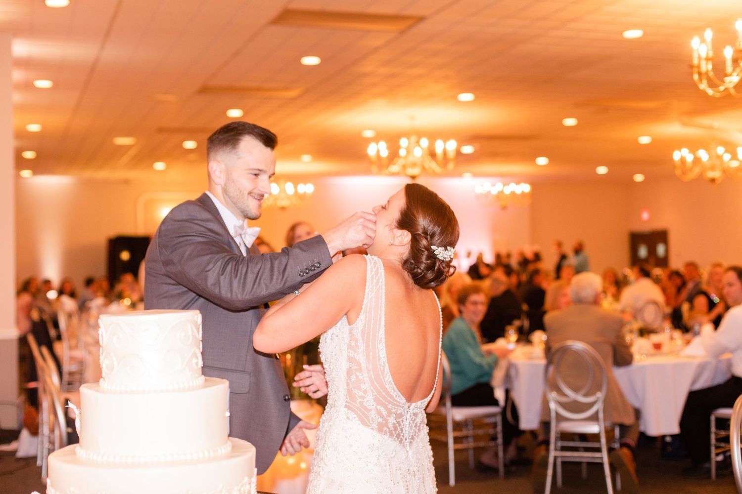 Elegant ballroom wedding reception with chandelier lighting and guest tables.