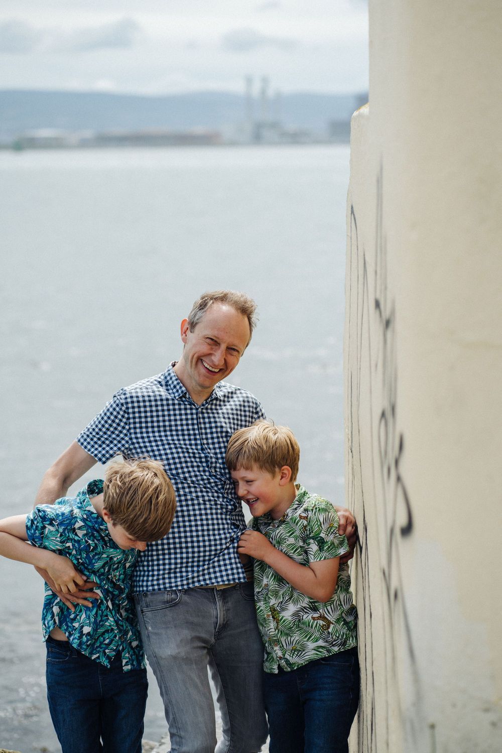 A playful moment captured against a white wall near the waterfront.