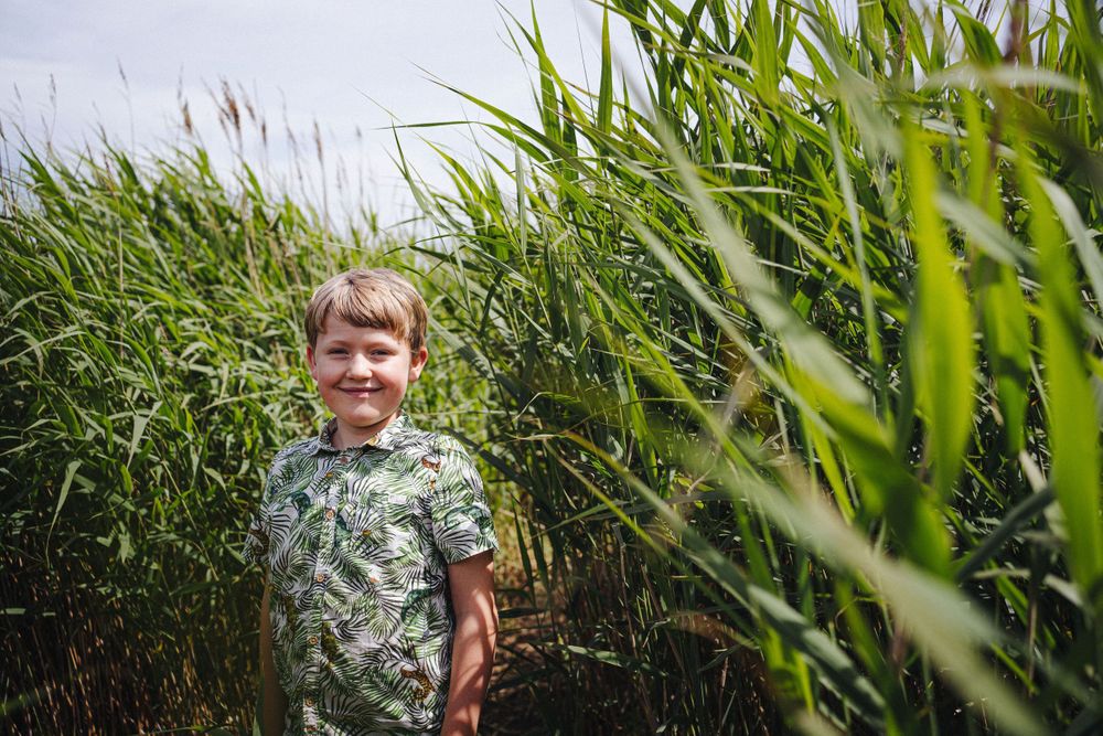 A candid portrait among tall green grass with stormy clouds overhead.
