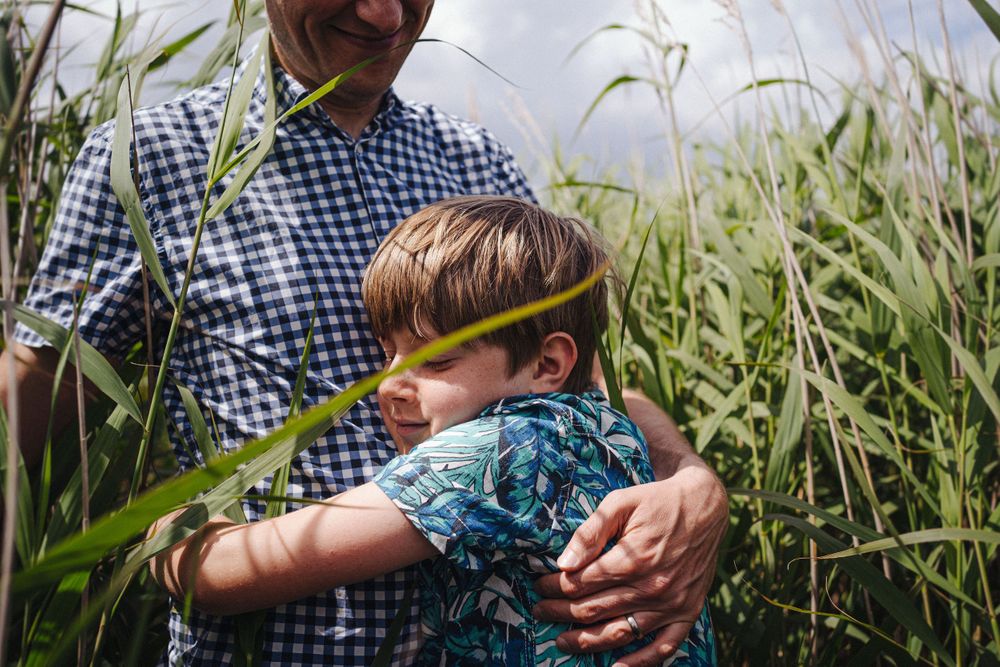 A tender moment shared in tall grass on a summer day.