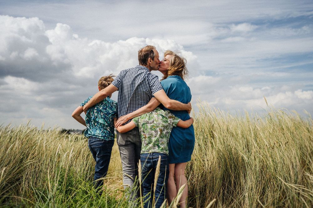 A loving embrace shared among coastal grass under blue summer skies.