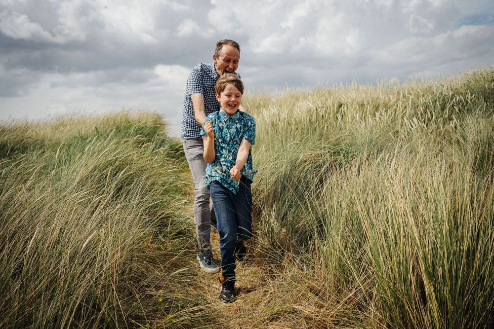 A playful walk through coastal dunes with tall grass swaying in the breeze.