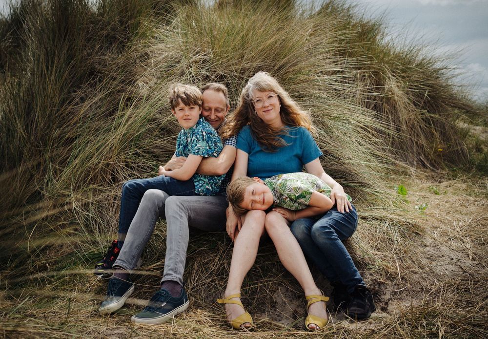 A relaxed family moment on grassy coastal dunes.