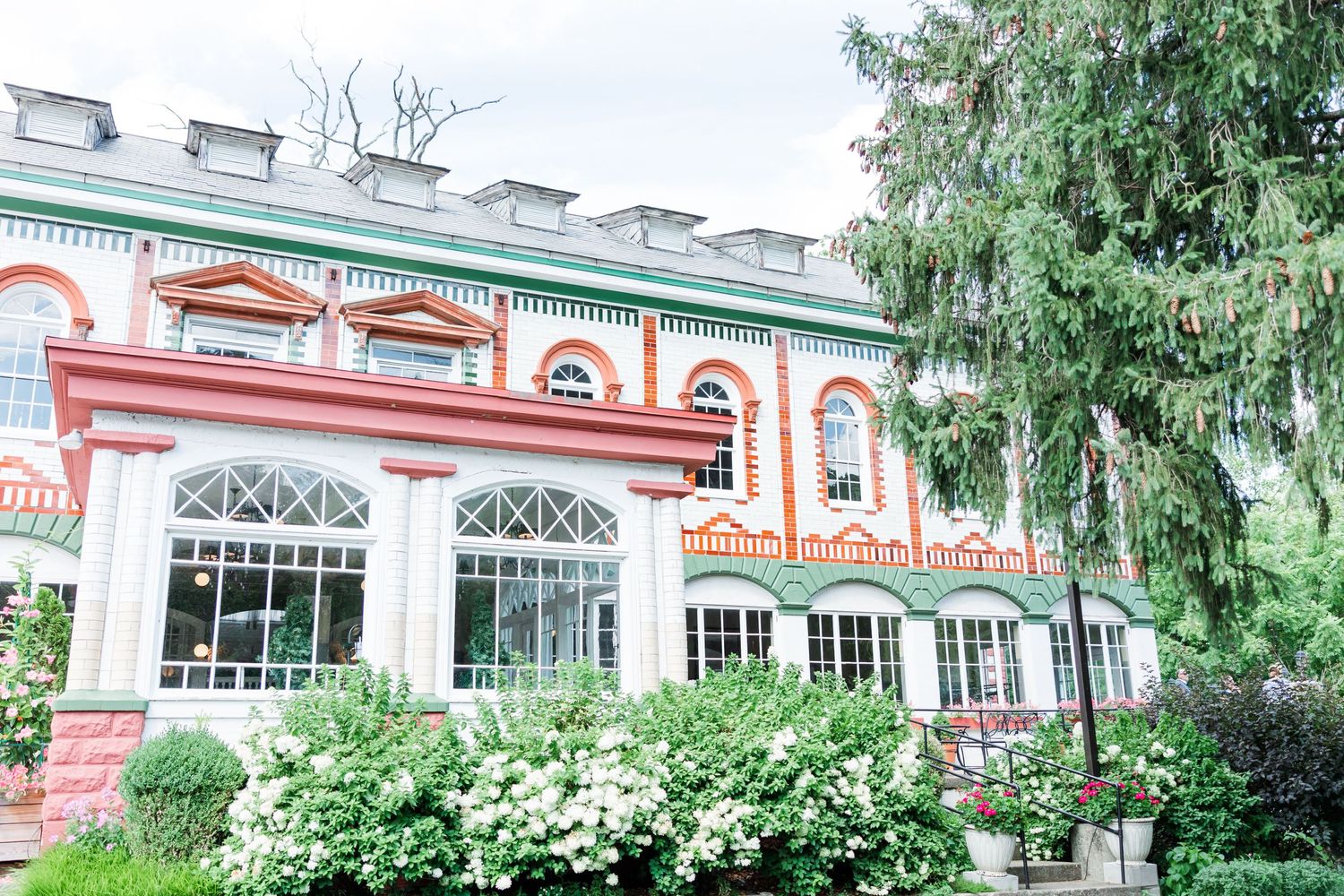 Historic mansion with colorful trim and arched windows surrounded by lush greenery.