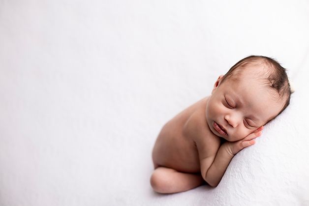 Peaceful sleeping newborn baby on white blanket in studio setting.