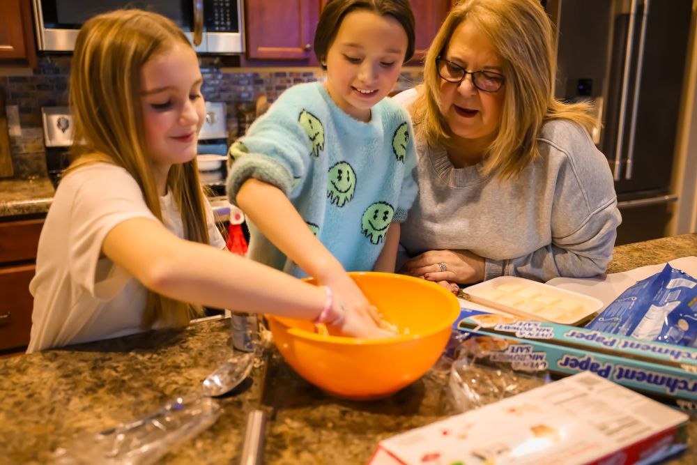People gathered around a kitchen counter working on a baking project together.