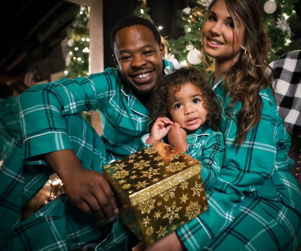 Family members in matching green plaid shirts opening Christmas presents together.