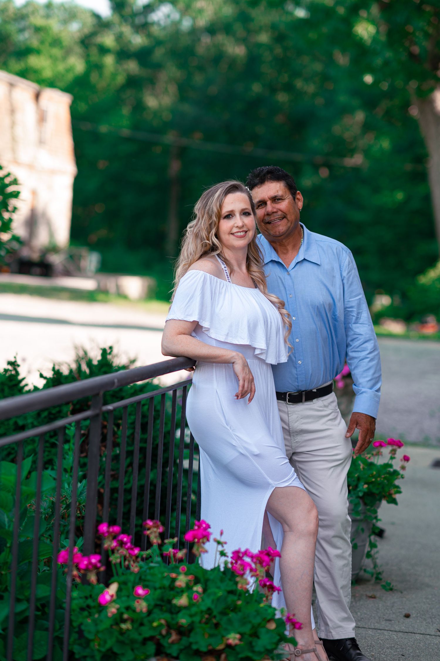 Romantic couple portraits on garden path with blooming pink flowers.