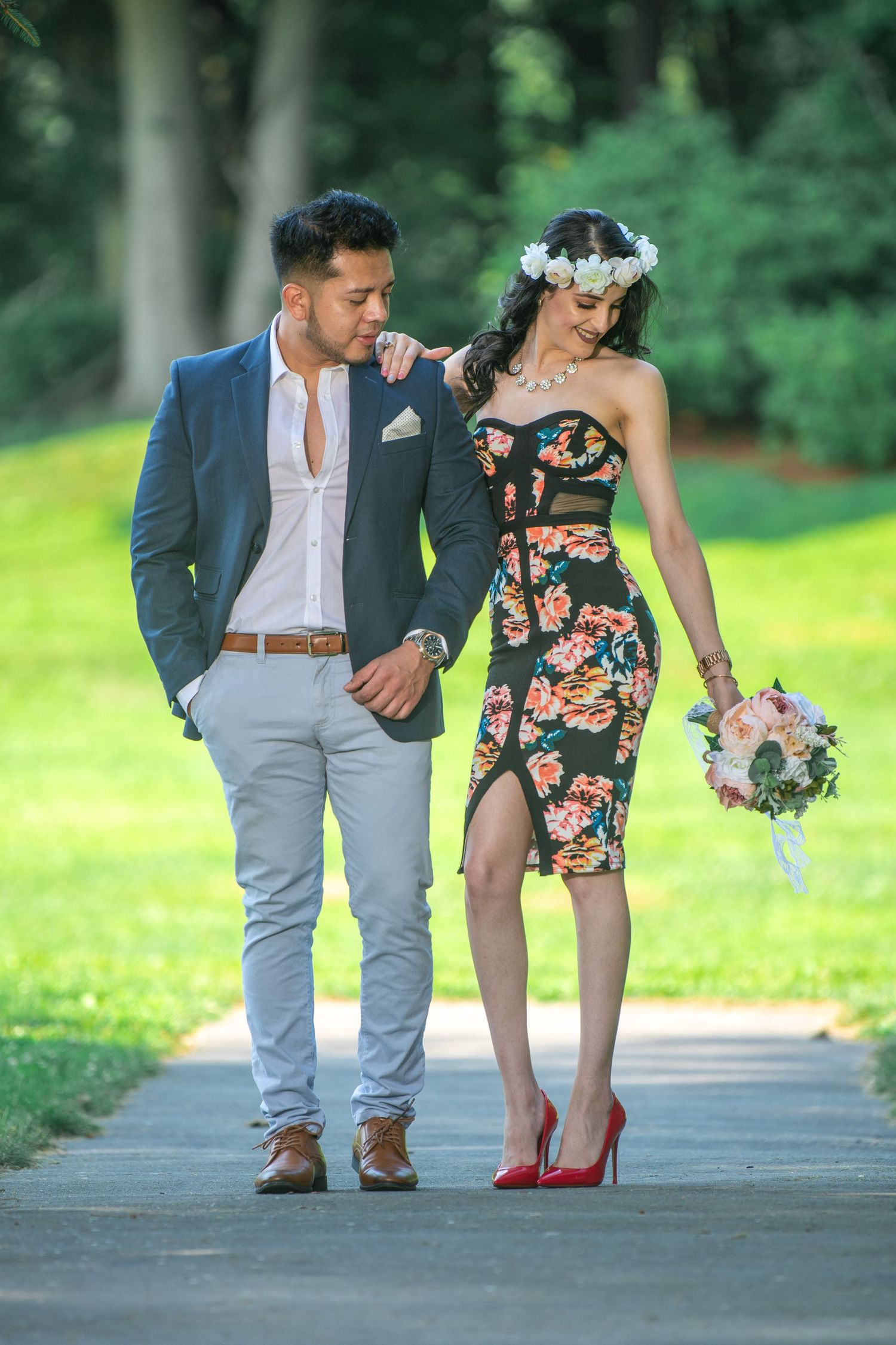 Elegant couple poses on garden path wearing coordinated formal attire.