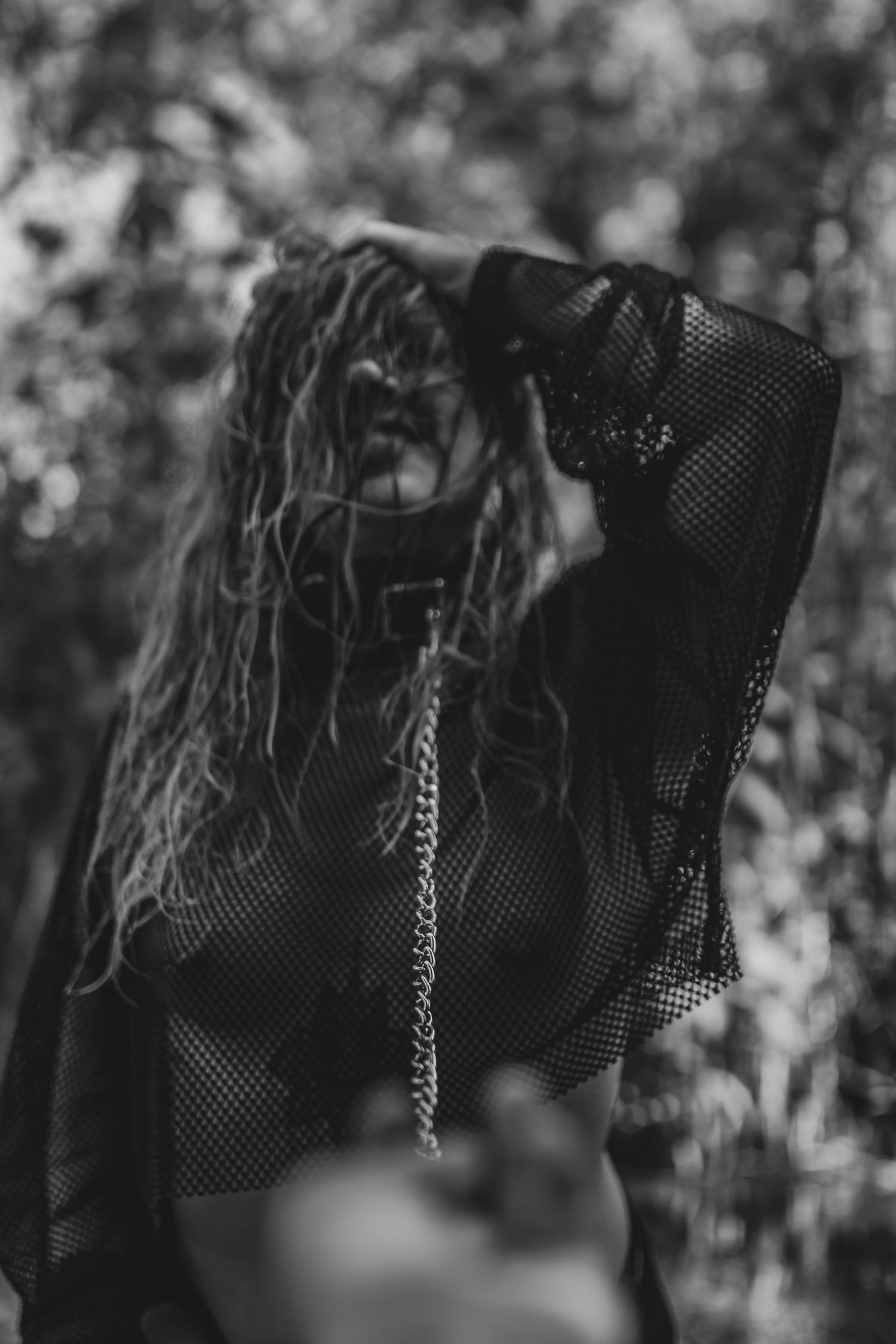 Artistic black and white portrait featuring mesh clothing and dramatic lighting.