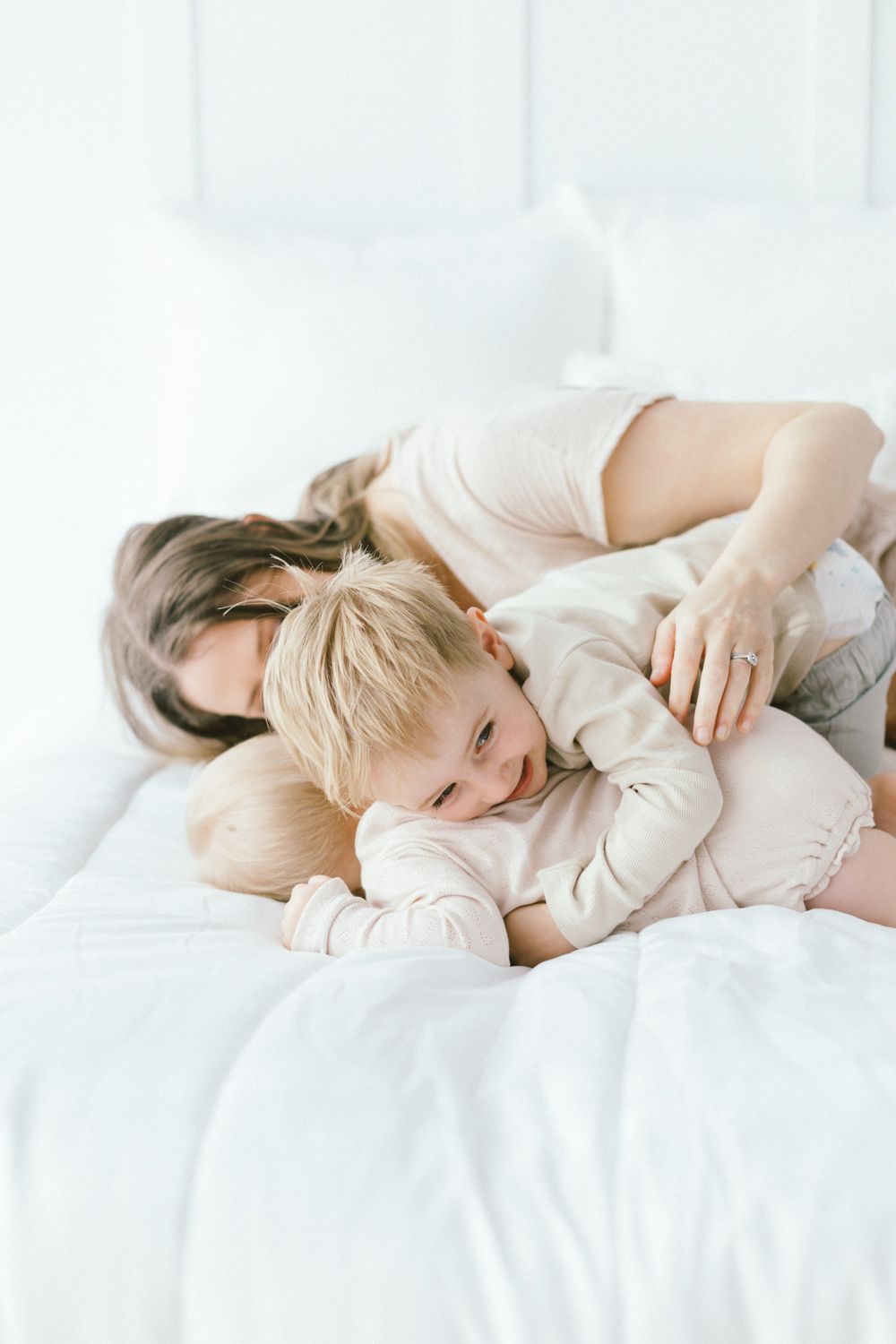 Intimate family moment captured in soft white tones as they rest together.
