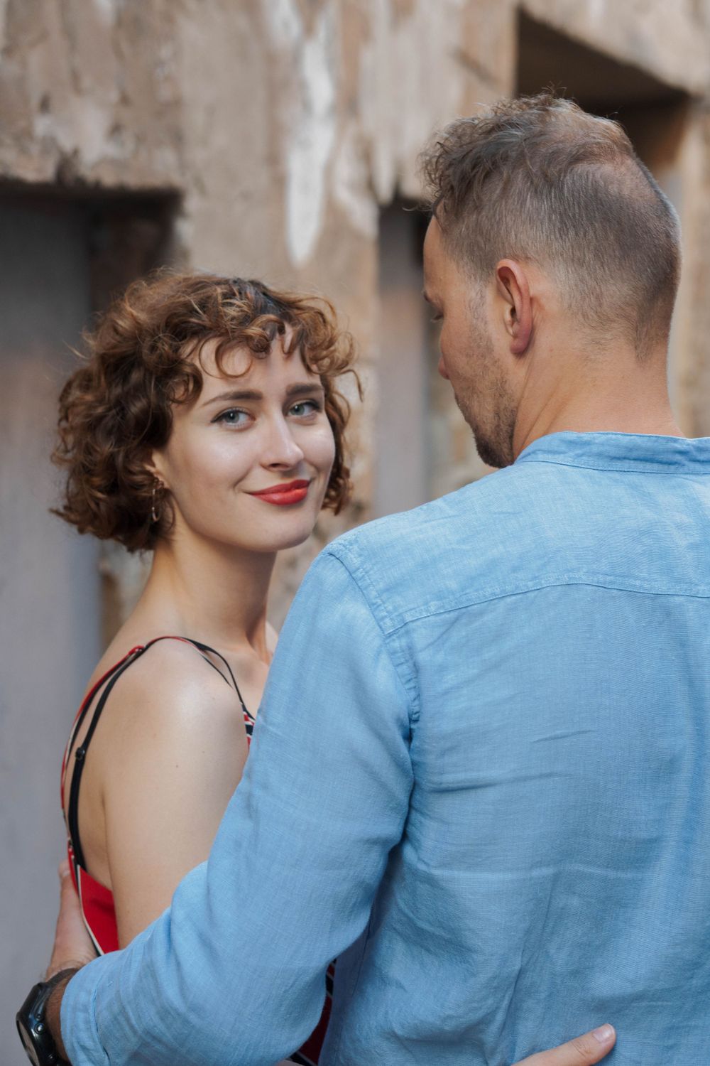 A woman looks towards the audience being hugged by a man.