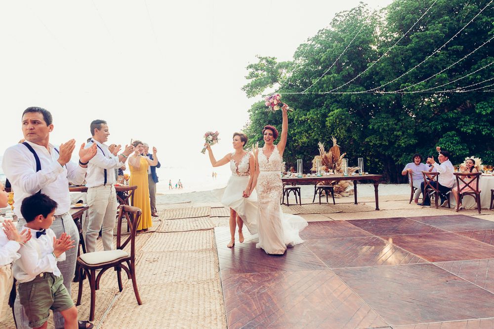 Outdoor wedding reception with guests celebrating on waterfront dance floor.