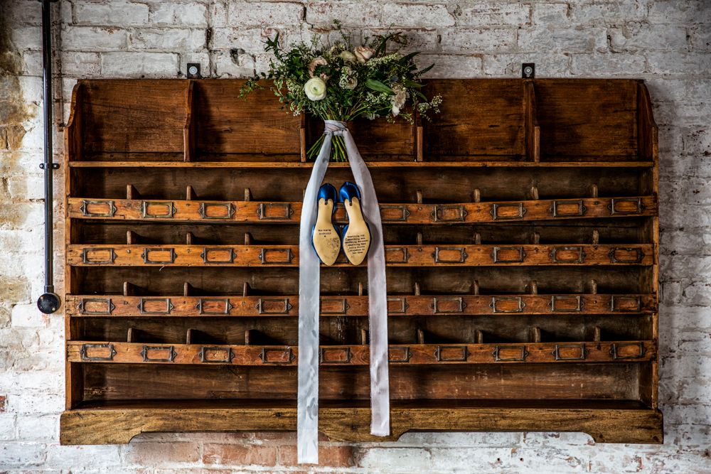 Wedding dress and floral arrangement hanging on rustic wooden board display.