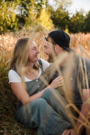 An intimate portrait of a couple sitting in tall grass during golden hour.