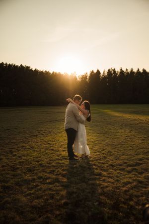 A romantic silhouette of a couple dancing in a field during golden hour.